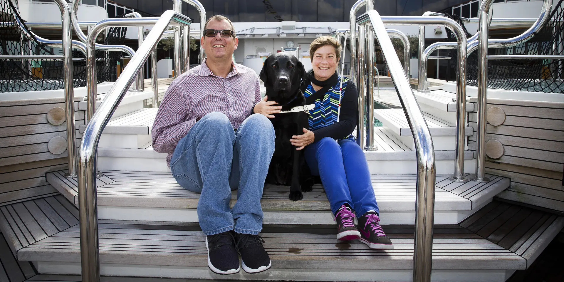 Corne en Connie zitten op het achtersteven van een boot samen met hun hulphond