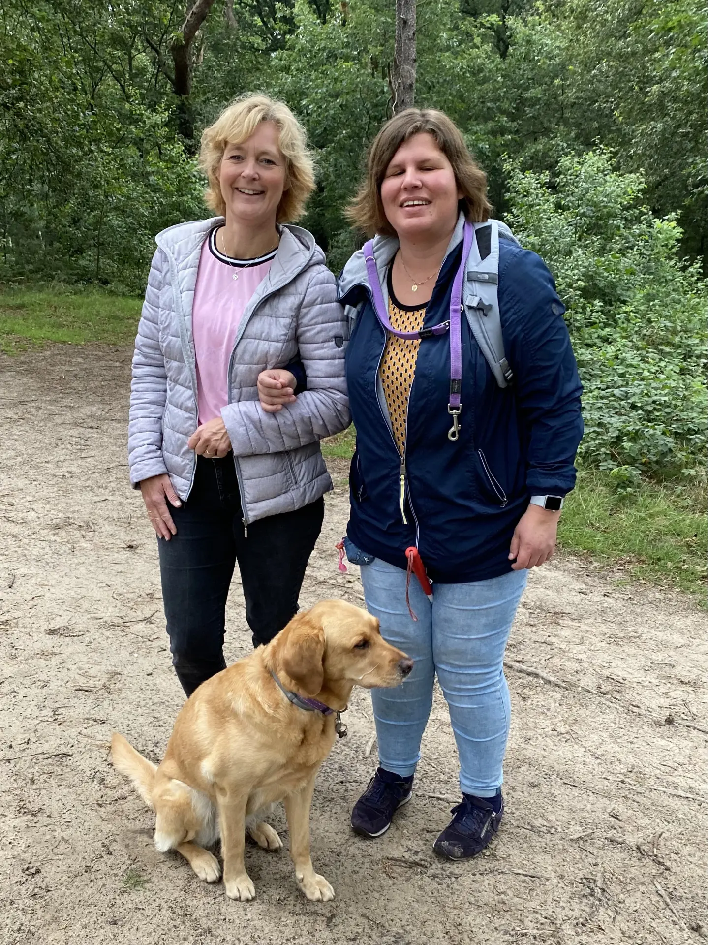 Pleegouder Joyce poseert samen met client Melanie en blindengeleidehond Ajonne