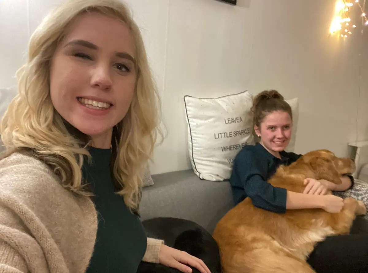 Sylvana en Janice zitten samen met hun blindengeleidehonden op de bank