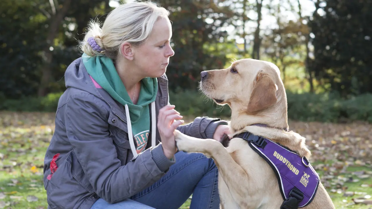 Joyce samen met haar assistentiehond Ursus die een poot tegen de hand van Joyce aanhoudt