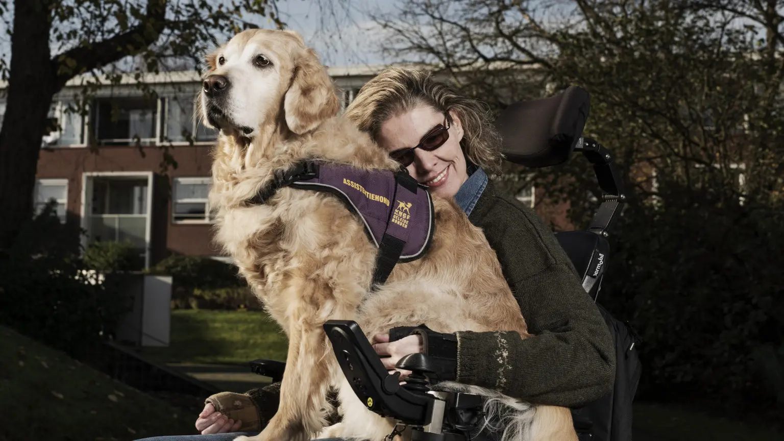 Sandra heeft haar assistentiehond Babbe op haar schoot terwijl ze posseren voor de camera