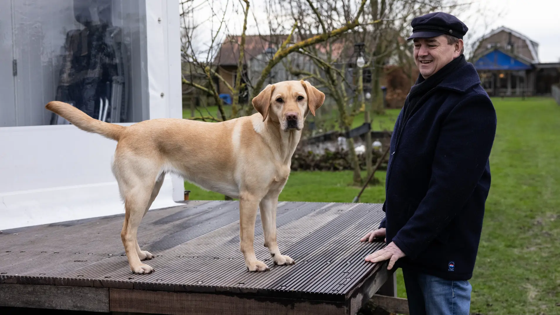 Ruud en blindengeleidehond Nuba staan buiten, waar Nuba op een houten platform staat