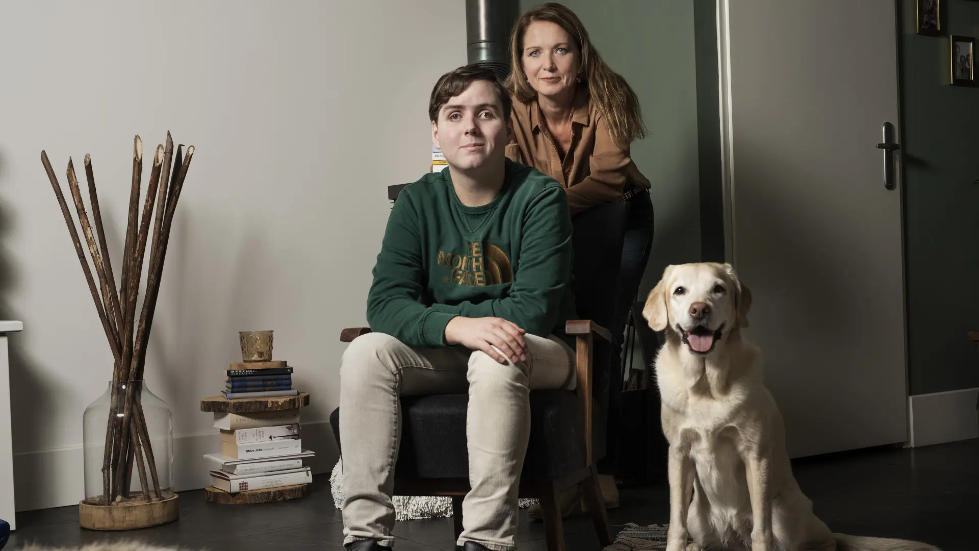 Joric, zittend op een stoel met zijn moeder achter hem en naast hem zit zijn buddyhond Zinzi