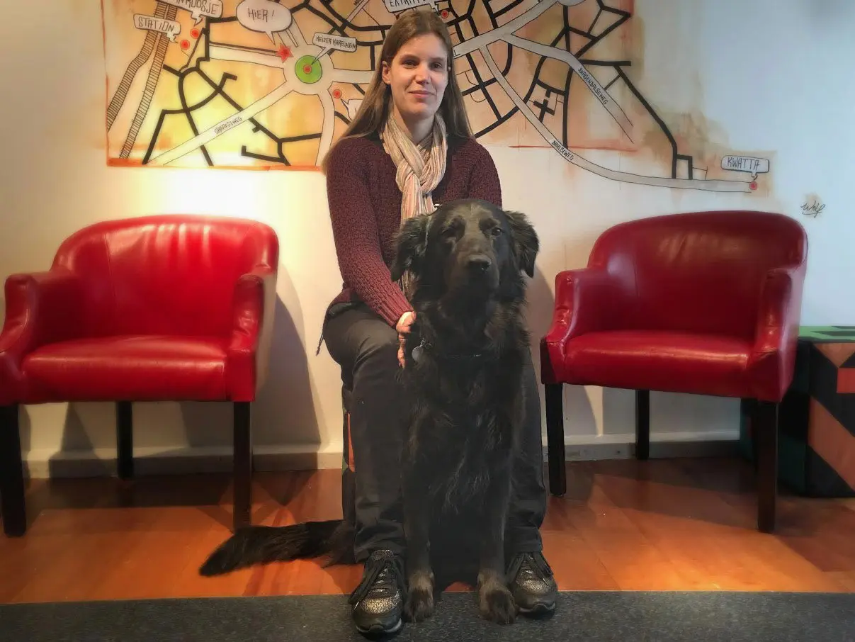 Doreen zit in een kuipstoeltje met haar blindengeleidehond voor zich.