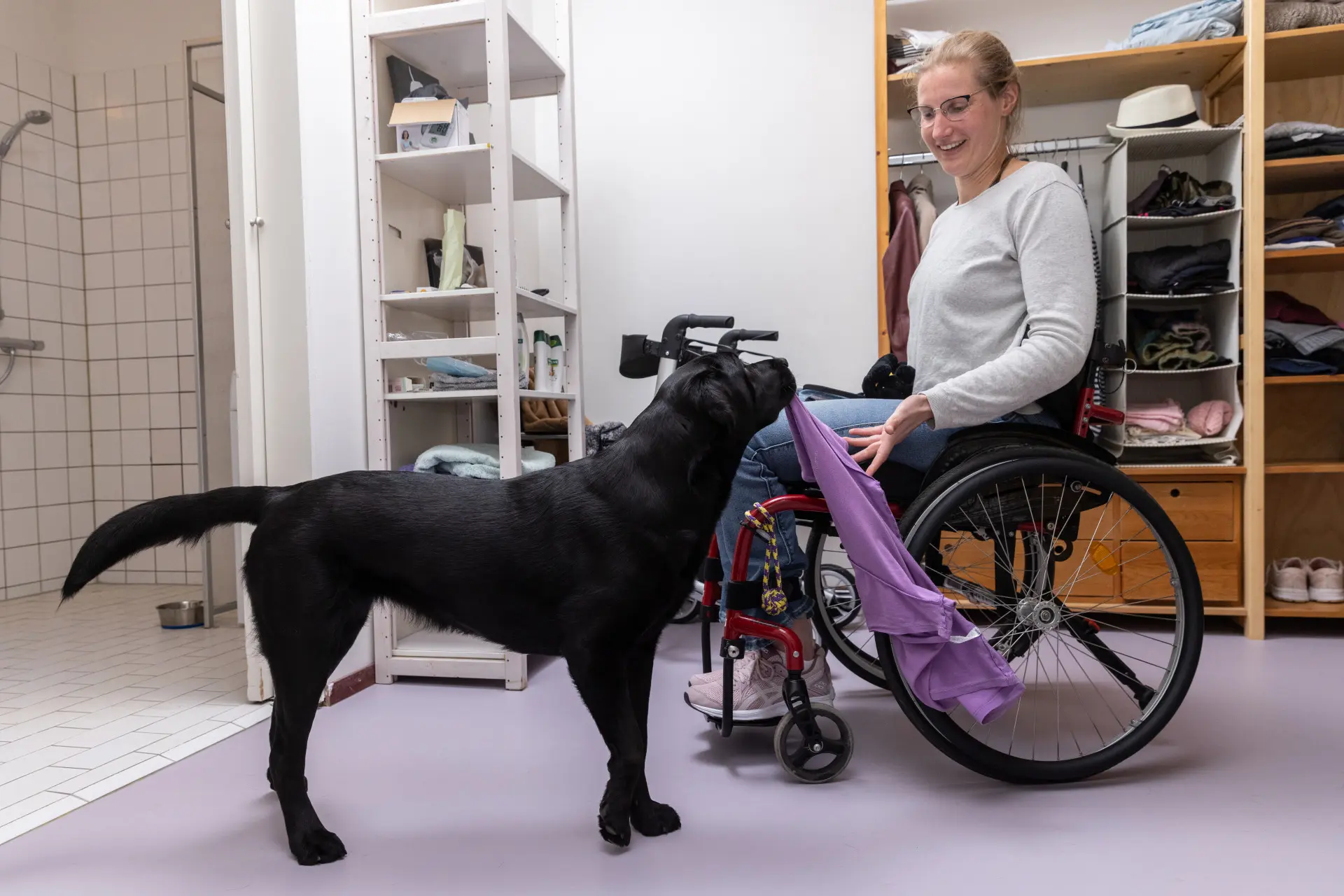 Jissa geeft een shirt aan Nynke die in haar rolstoel zit.