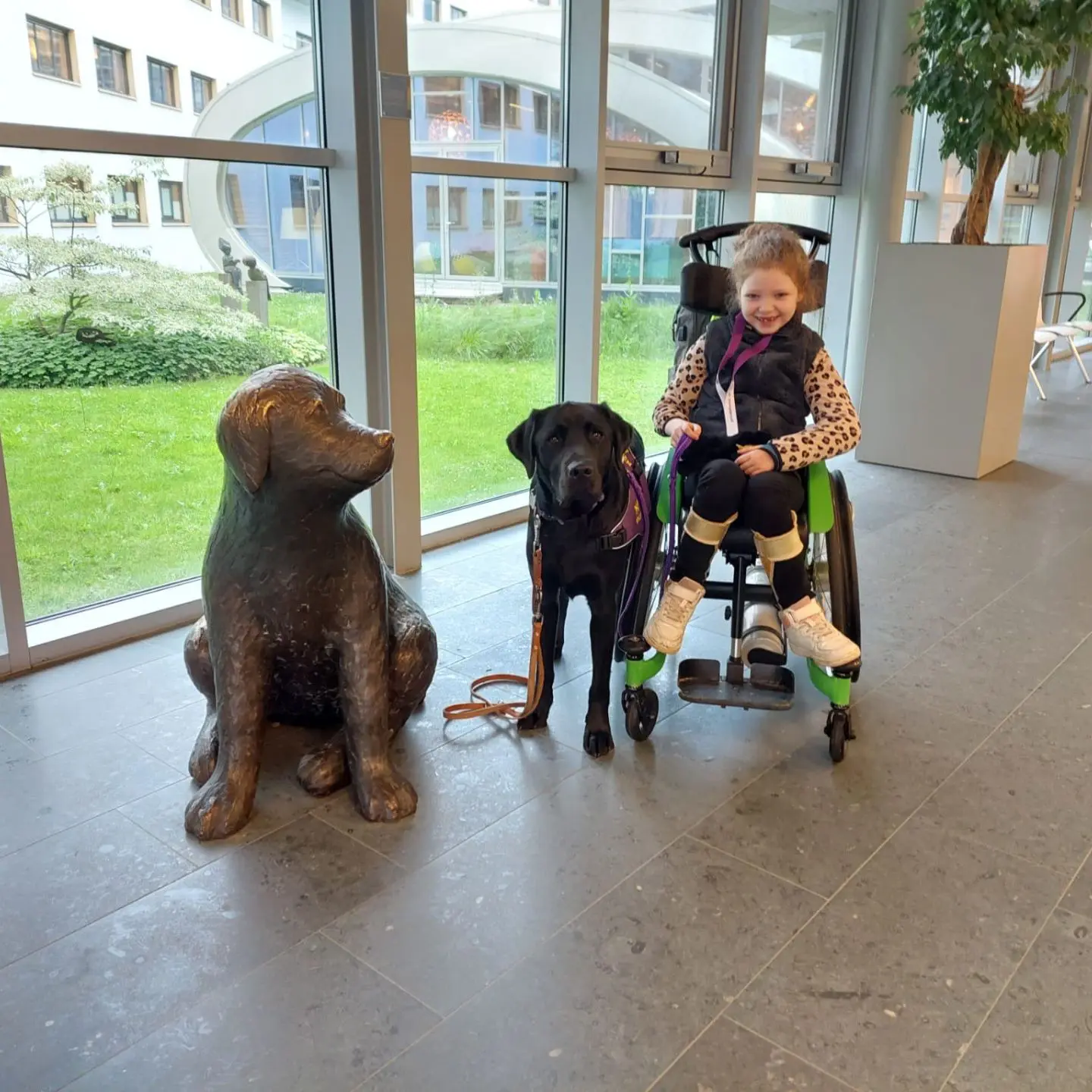 Memphis en Elin samen in de gang van een ziekenhuis, naast hun staat een standbeeld van een hond