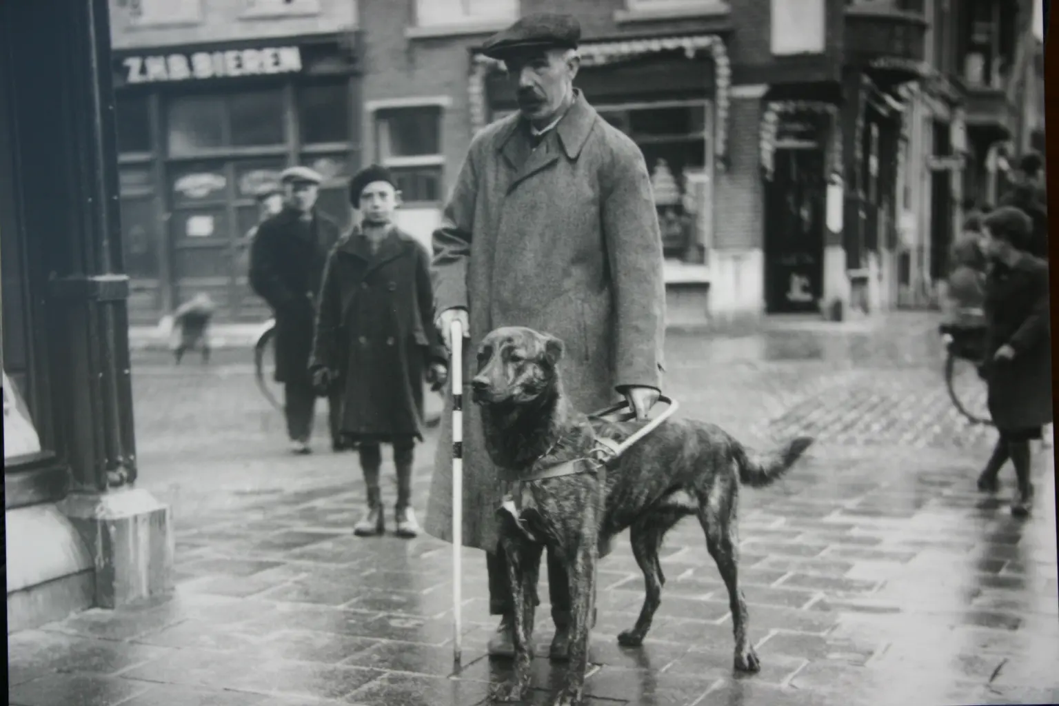 historische zwartwit foto van man met zijn geleidehond op straat