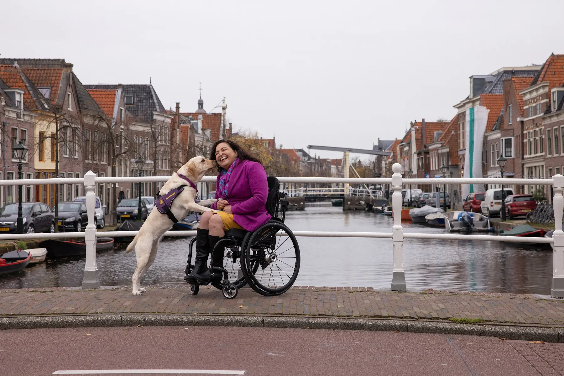 Katya staat met haar voorpoten op de schoot van Claudia terwijl ze poseren op een brug over een gracht