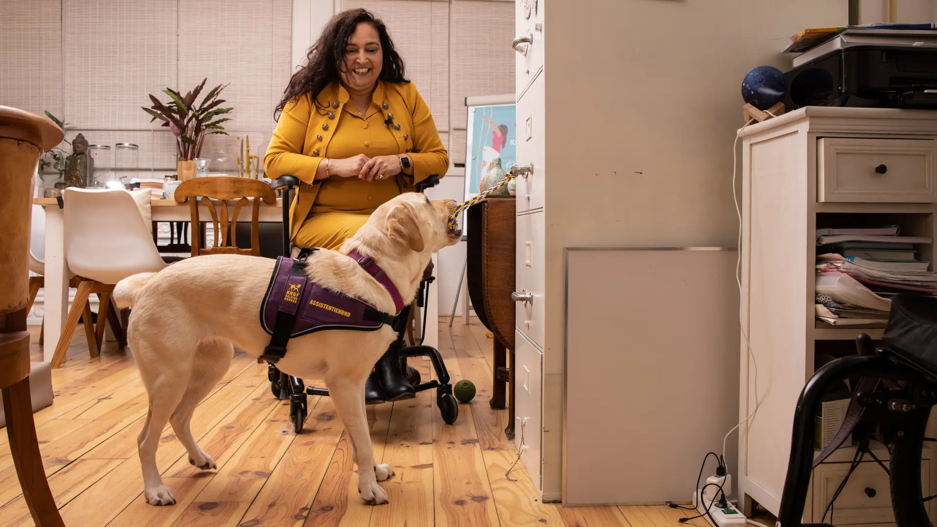 Assistentiehond Katya opent een kast terwijl Claudia toekijkt.