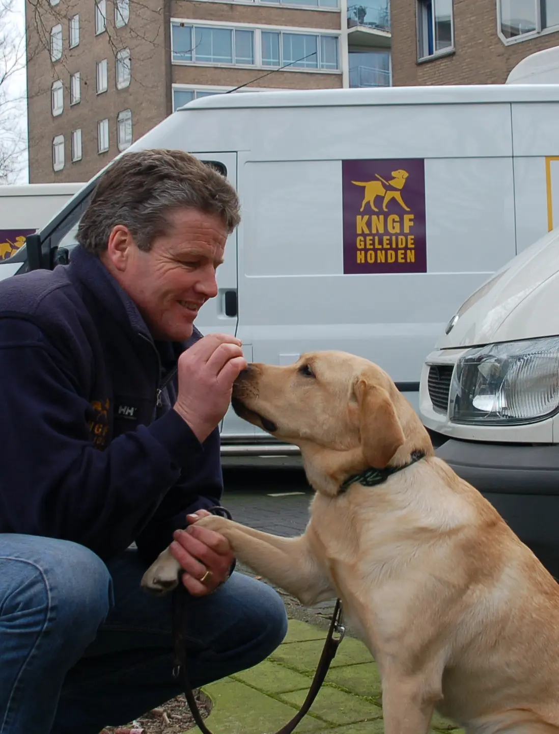 Trainer Kees geeft een koekje aan een hulphond in opleiding
