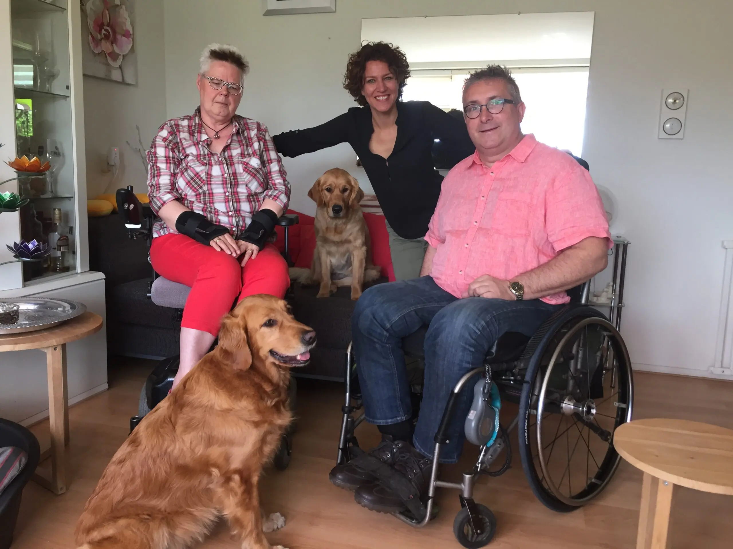Marjanne en Hub in hun woonkamer met hun assistentiehonden Bizzy en Varaya