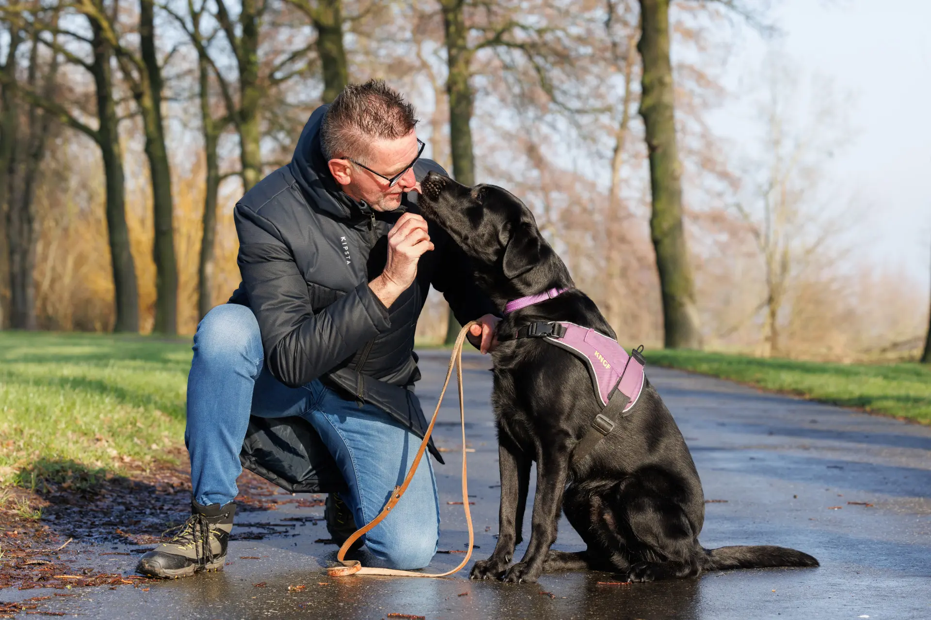 Ruud zit gehurkt op straat en kijkt zijn PTSS assistentiehond Zorba indringend aan