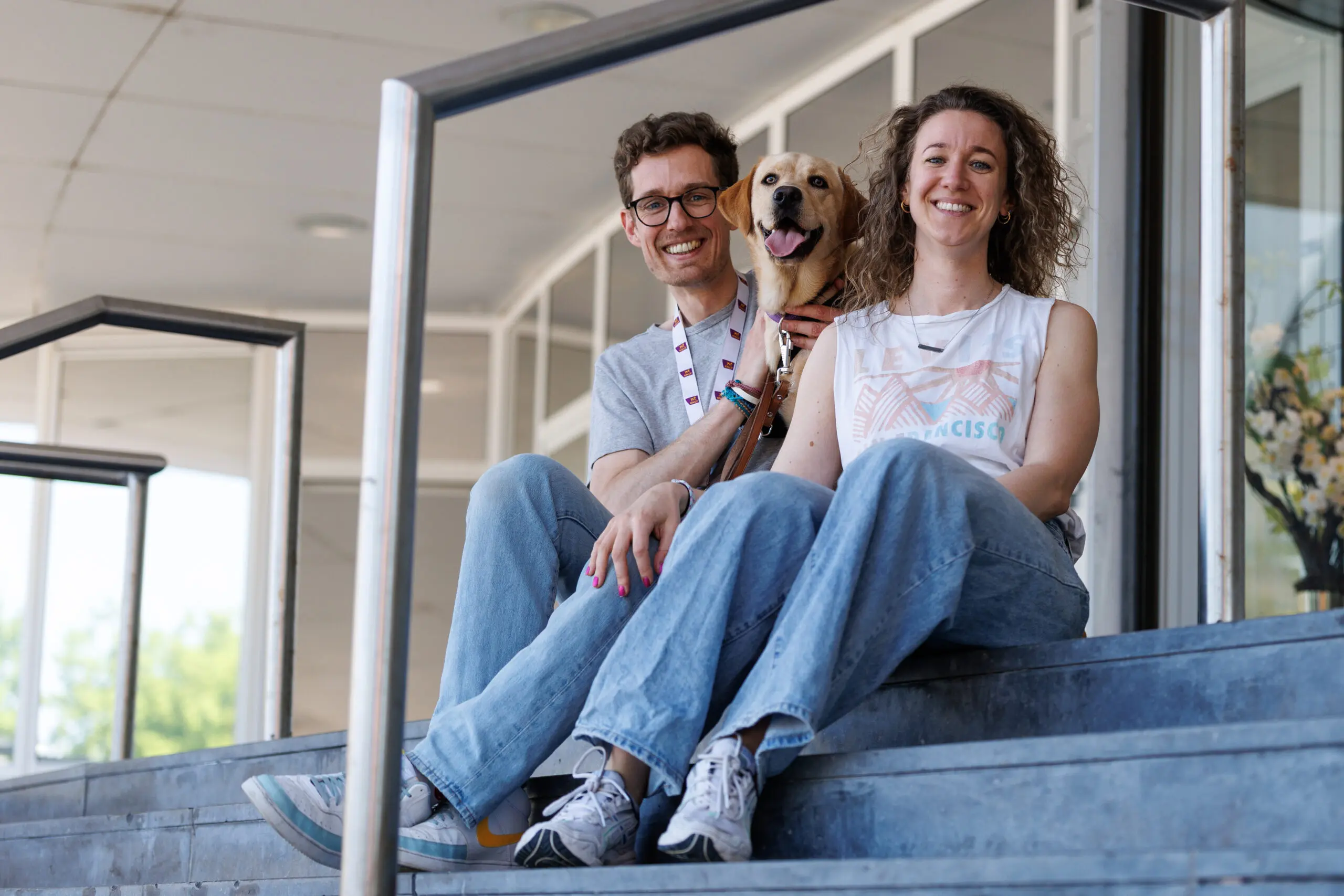Hulphond in opleiding Japi met zijn pleeggouders Ayolt en Kirsten zittend op een trap