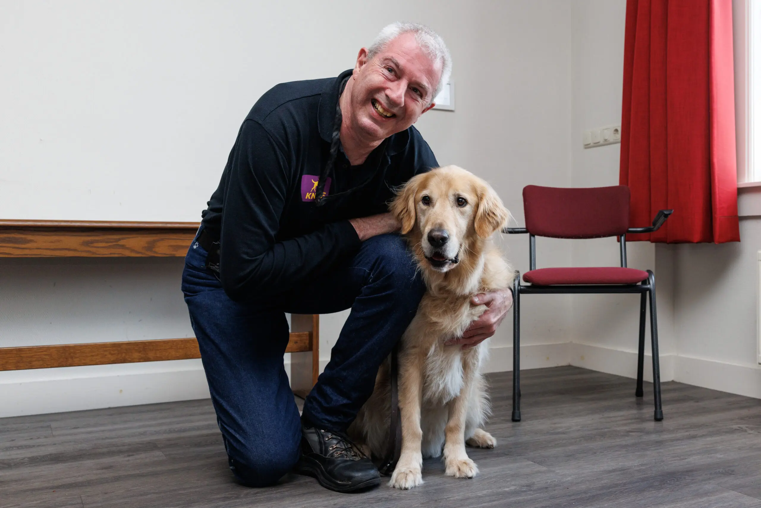 Man zit gehurkt naast zijn langharige geleidehond