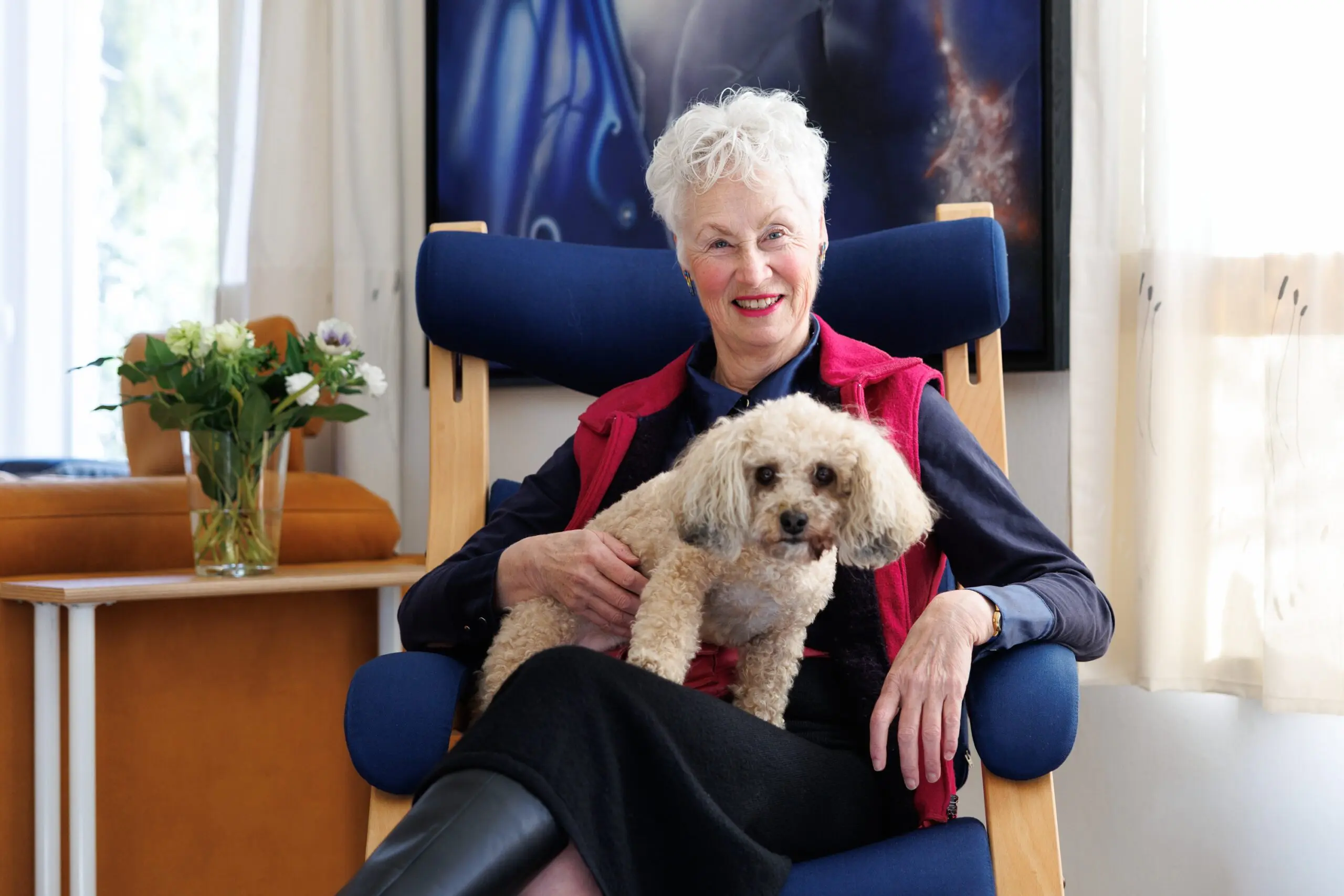 portret van vrouw in huiselijke omgeving met een hondje op schoot.