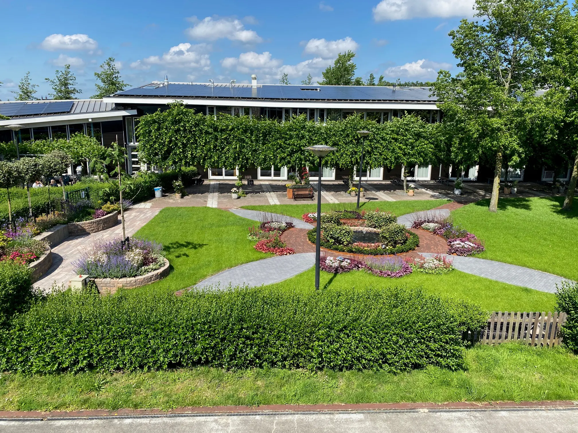 de tuin van KNGF van boven gezien met in het midden een vijvertje en de bloembedden en looppaden eromheen als een bloem.