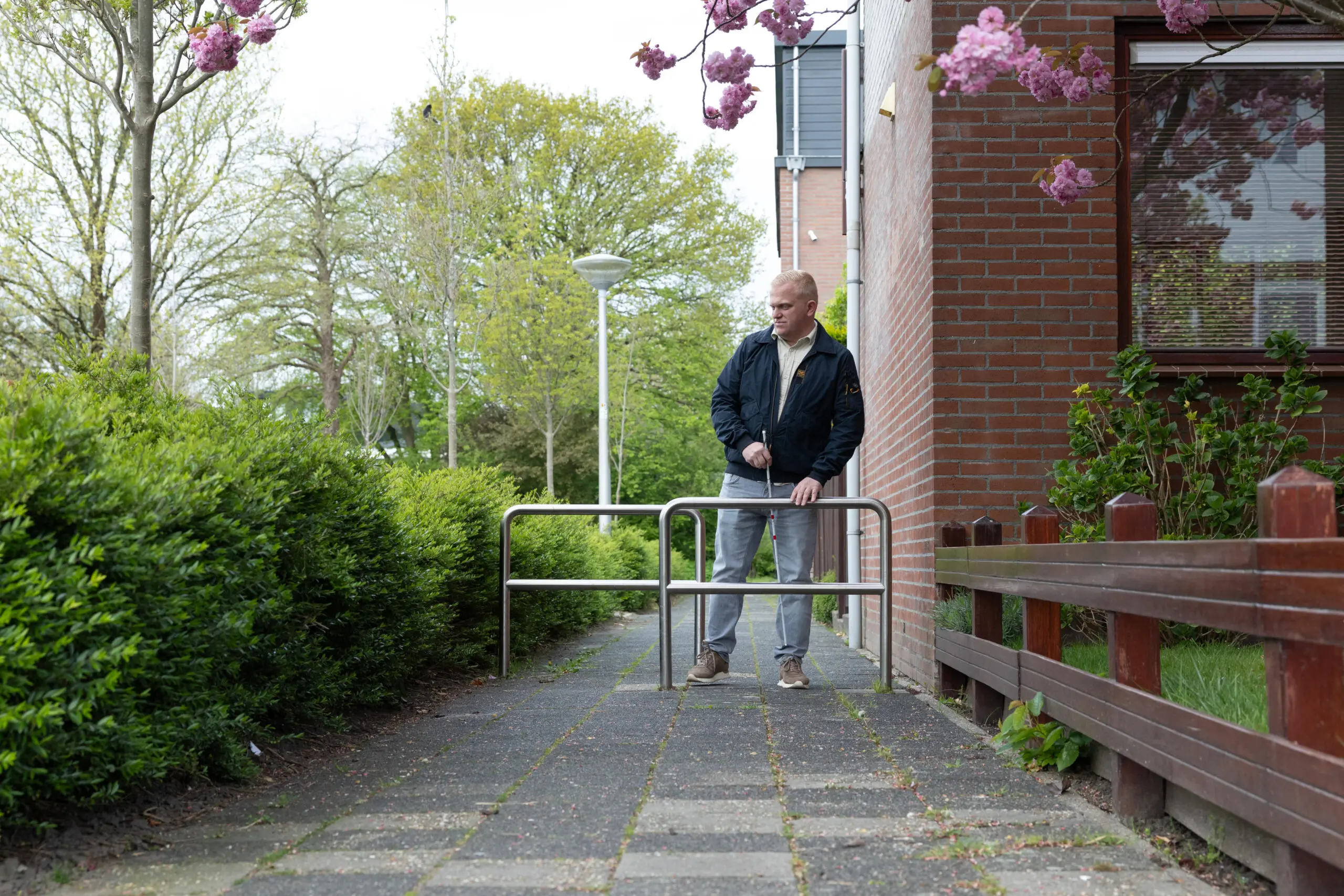 Client Maikel loopt met een taststok tussen twee obstakels door op straat