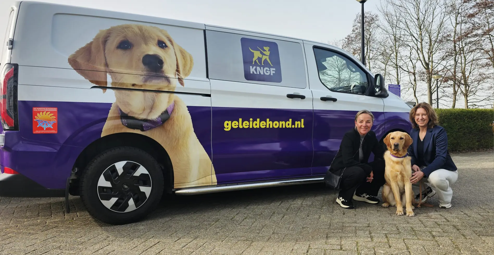2 vrouwen en een hond zitten naast een nieuwe elektrische trainingbus