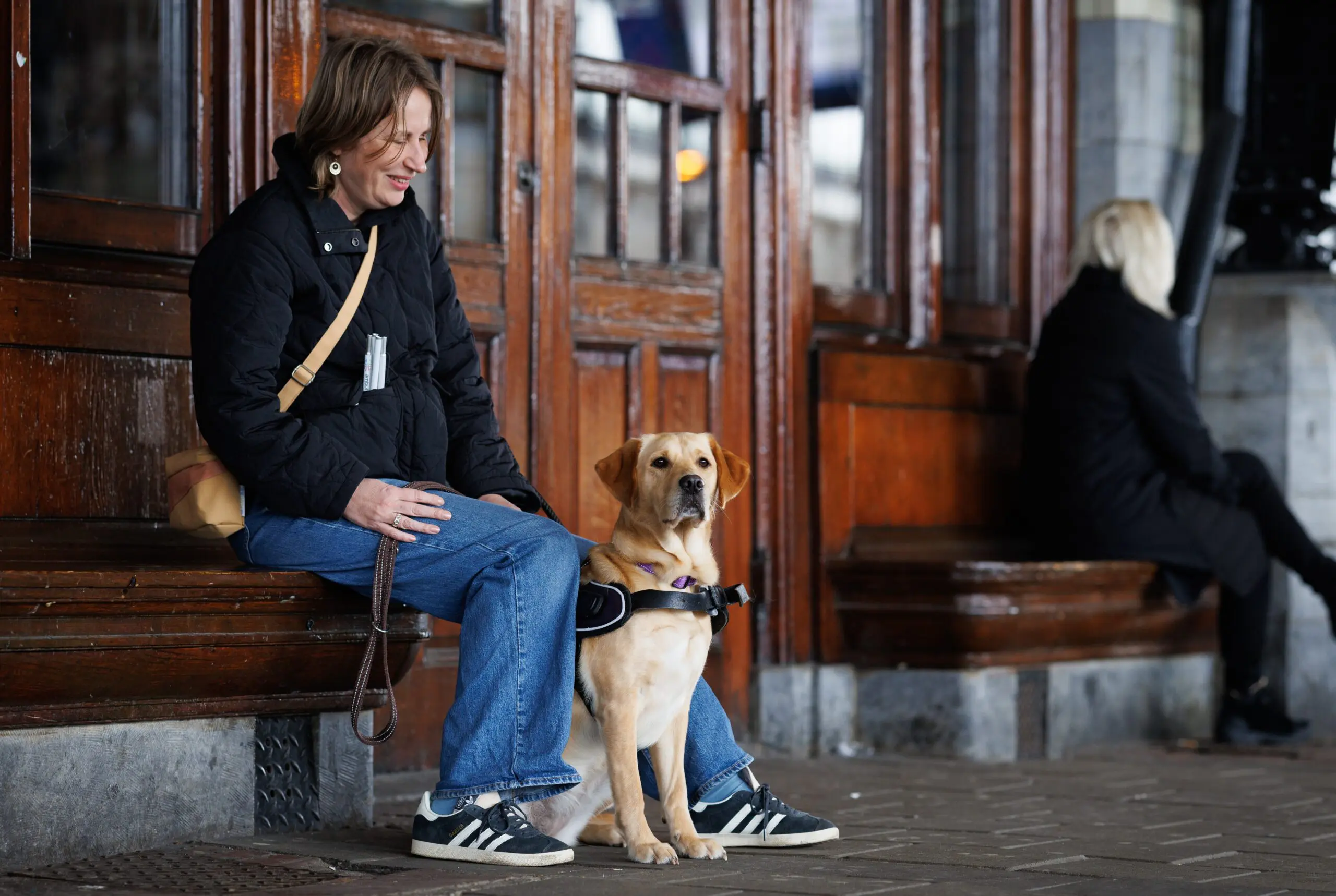 Elian en blindengeleidehond Lola zitten op een bankje