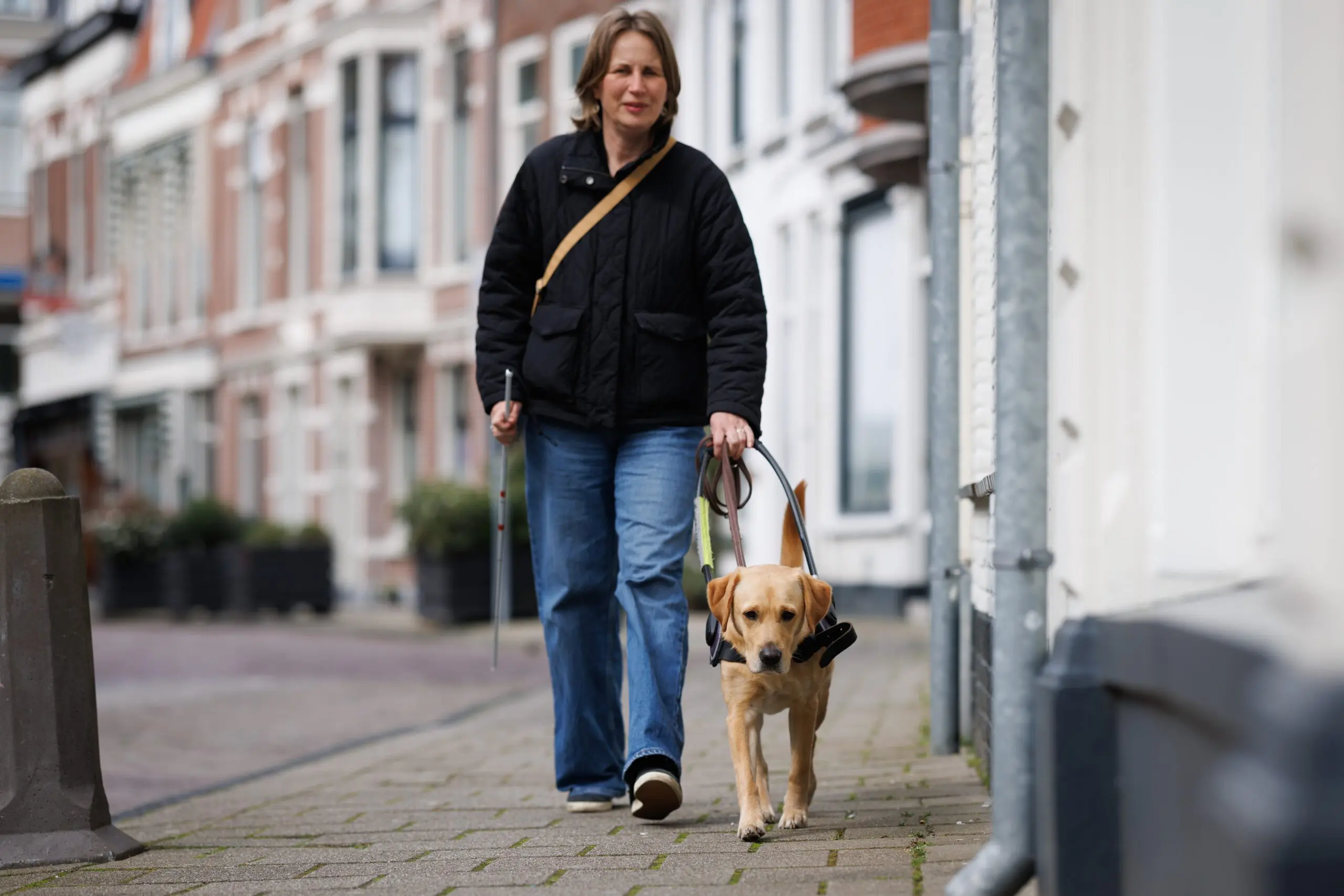Elian loopt met blindengeleidehond Lola over straat