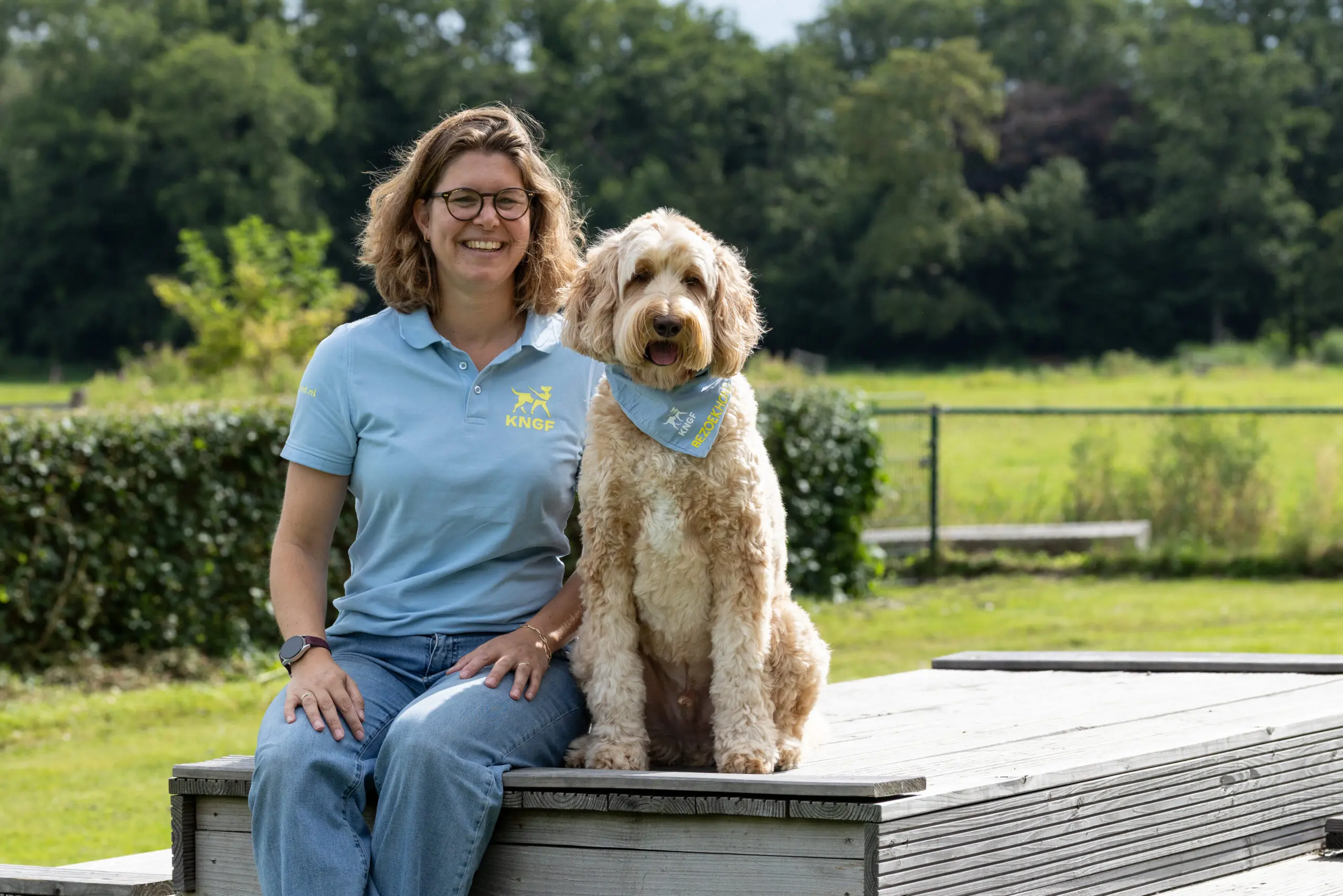 Laura, begeleider bezoekhonden, en haar bezoekhond Flynn, zitten op een bankje