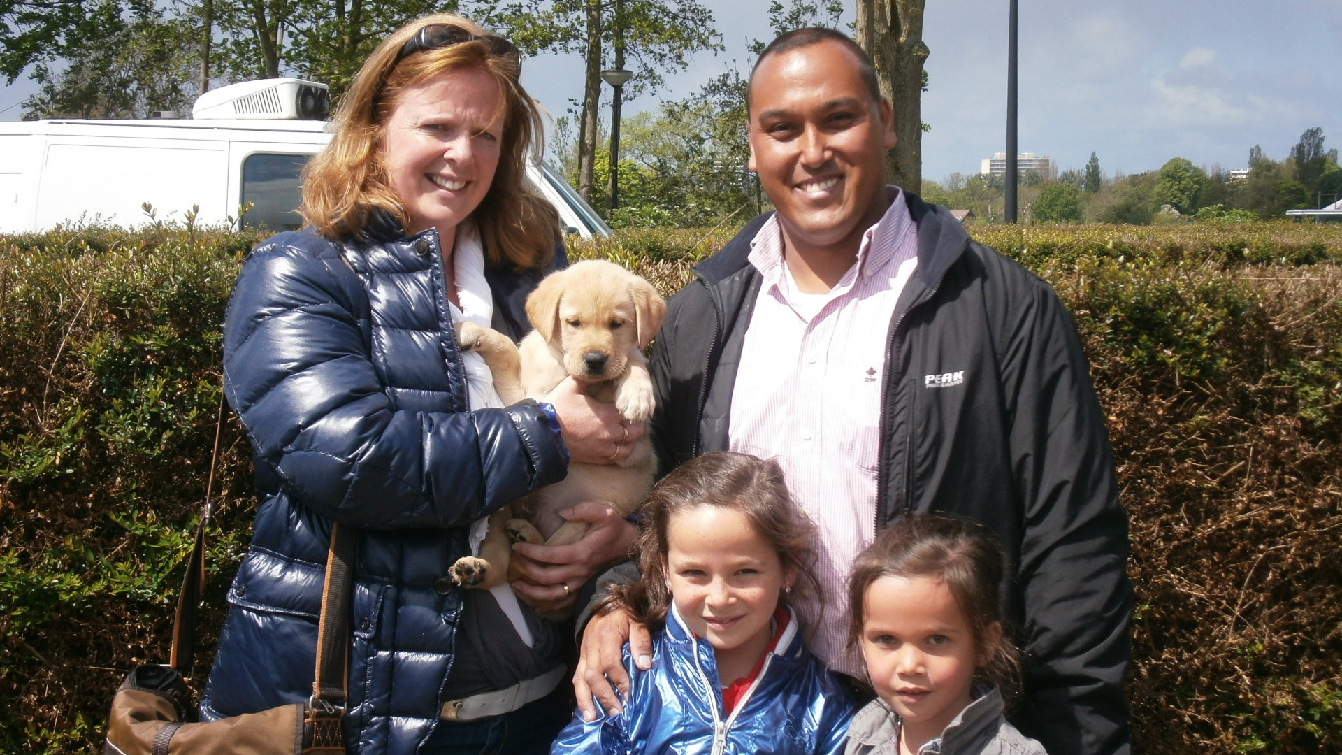 Familie hooper, ouders en twee kleine dochters, met de pup die zij net hebben opgehaald in hun armen.