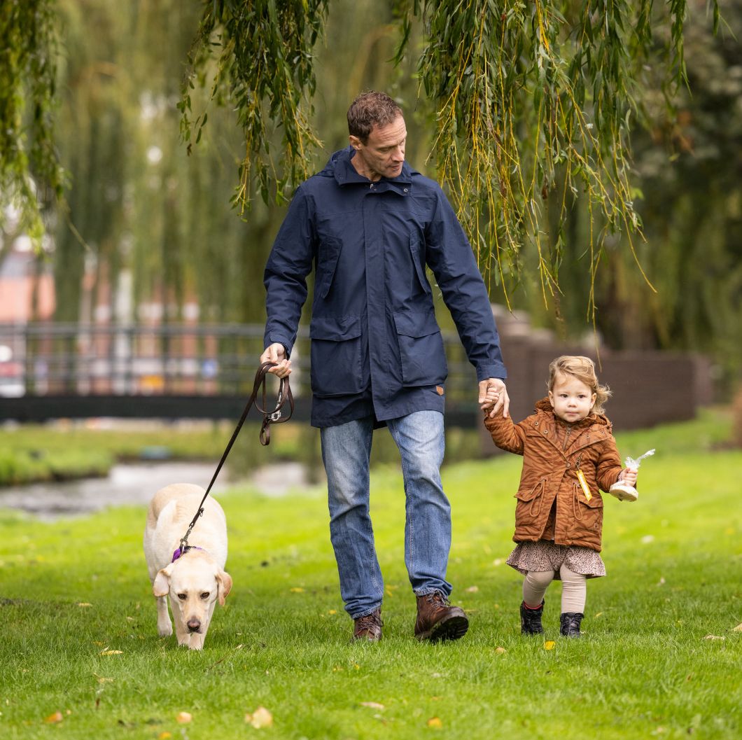 Erik loopt samen met zijn PTSS assistentiehond Bonsai en zijn dochter door het park