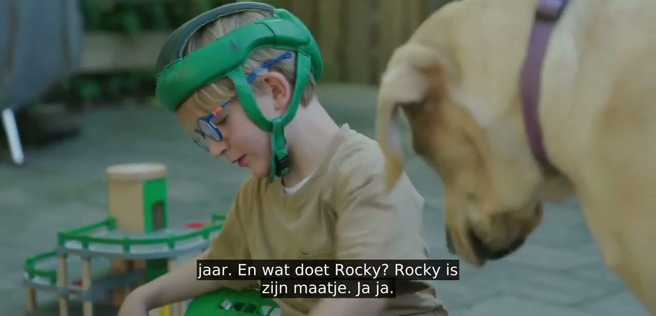 Seppe speelt op de grond terwijl zijn hulphond Rocky toekijkt