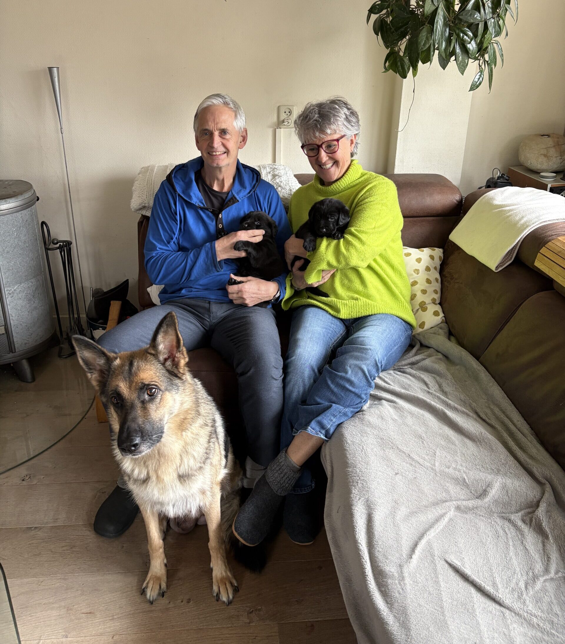 Ronald en Jantineke met pups op de bank, moederhond voor de bank
